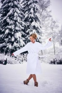 Une femme en robe blanche marchant dans la neige dans l'établissement Domaine Des Hautes Fagnes, à Ovifat