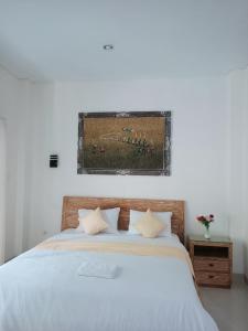 ein Schlafzimmer mit einem weißen Bett mit einem Bild an der Wand in der Unterkunft Adijaya homestay in Seminyak