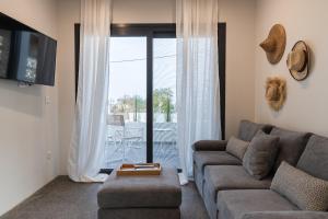 ein Wohnzimmer mit einem Sofa und einem Fenster mit einer Terrasse in der Unterkunft Luxury Villa in Center of Agioi Theodoroi in Agii Theodori