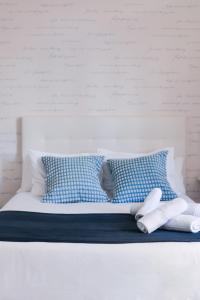 Una cama blanca con almohadas azules y blancas. en Larios Premium Apartments en Málaga