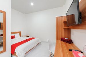 Schlafzimmer mit einem Bett und einem Flachbild-TV in der Unterkunft RedDoorz Plus Syariah near Mall Boemi Kedaton Lampung in Kedaton