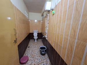 a bathroom with a toilet in a tiled wall at Wonderhills lodge in Hinjewadi