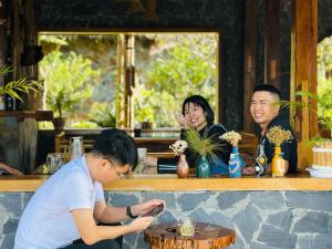 Ein Mann, der an einer Bar sitzt und ein Handy ansieht. in der Unterkunft Mường Lò Retreat Nghia Lo in Yên Bái