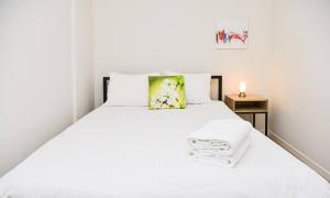 un letto bianco con lenzuola bianche e un cuscino giallo di Modern apartment Dora a Mendrisio