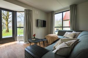 sala de estar con sofá azul y ventanas grandes en luxe vakantiehuisje - sauna - natuur - strand en Ewijk