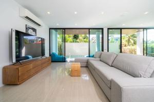 un soggiorno con divano e TV a schermo piatto di 3-Story Pool Villa Katahan UTK B4 just 7 min walk to Kata Beach a Kata Beach