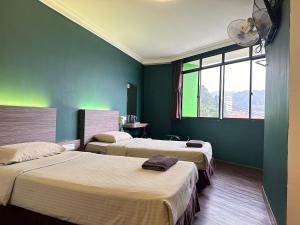 two beds in a room with green walls at Parkland Hotel in Brinchang