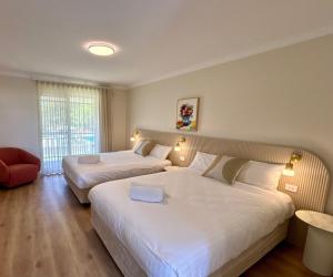 una camera d'albergo con due letti e una sedia di The Timothée Resort a Busselton