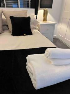 a white bed with a black pillow and towels on it at 2 bedroom modern flat in Romsey in Romsey