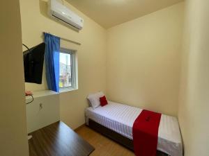 a small bedroom with a bed and a window at RedDoorz at Ramelau near AP Pettarani in Makassar