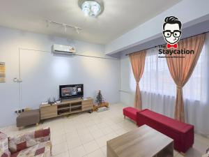 sala de estar con TV y sofá rojo en Staycation Homestay 33 Floridale Condominium near viva city, en Kuching