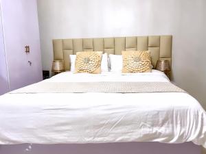 1 cama grande con sábanas y almohadas blancas en Cozy Condo Unit in Puerto Princesa City near PPS Airport, en Puerto Princesa City