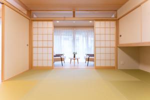 Stagione Hakone Yumoto Villa スタジオーネ箱根湯本VILLA في هاكوني: غرفة بجدران بيضاء وطاولة وكراسي