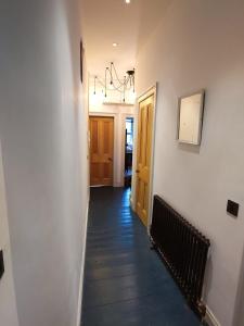a hallway with white walls and wood floors and a chandelier at Arthur's Seat View in Edinburgh