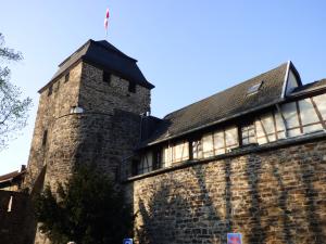 un ancien bâtiment en briques avec un drapeau en haut dans l'établissement "Zum Torwächter" im Niedertor Ahrweiler, à Bad Neuenahr-Ahrweiler