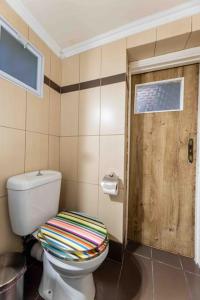 a bathroom with a toilet and a wooden door at Nagias cozy garden home in Athens