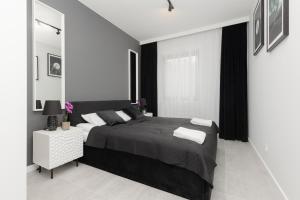 um quarto preto e branco com uma cama grande em Apartment with Balcony by the Park in Łódź by Renters Prestige em Łódź