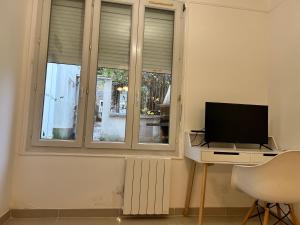 a living room with a television and a desk with a computer at Grand logement Centre Ville Massy in Massy