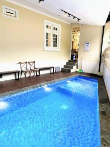 a large blue swimming pool with two chairs and a table at Cottonwood Bed & Breakfast House Bandung in Bandung
