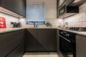 a kitchen with black cabinets and a sink at Amazing Property in Zone 1 in London