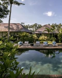 a resort with a swimming pool and two chairs at Bedulu Cliff Estate Villas Complex Ubud in Ubud