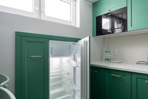a kitchen with green cabinets and a refrigerator at Nowy Świat 22 Luxury Apartment in Warsaw