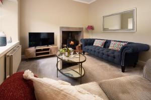 ein Wohnzimmer mit einem blauen Sofa und einem Fernseher in der Unterkunft Birch Cottage in Cockburnspath