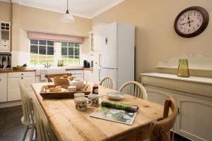 cocina con mesa de madera con sillas y reloj en Birch Cottage, en Cockburnspath