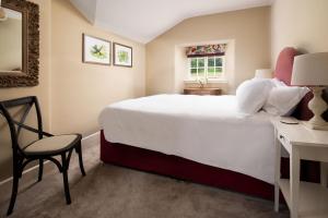 a bedroom with a large white bed and a chair at Birch Cottage in Cockburnspath