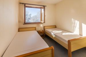 Duas camas num pequeno quarto com uma janela em Flat Synerveda em Megève