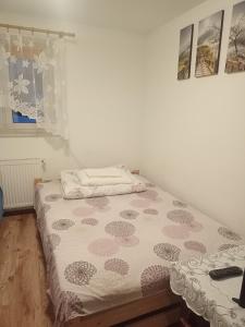 ein kleines Schlafzimmer mit einem Bett mit einer weißen und rosa Tagesdecke in der Unterkunft U Gabrysia i Tatiany in Ustrzyki Górne