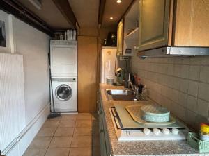 een kleine keuken met een wastafel en een wasmachine bij Aan de Dijk in Dordrecht