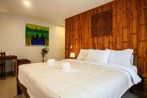 a bedroom with a large white bed with a wooden headboard at Lanta Thai Homestay in Ko Lanta