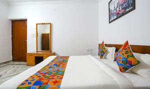 a bedroom with a large white bed with a mirror at FabExpress Premium Rooms in New Delhi