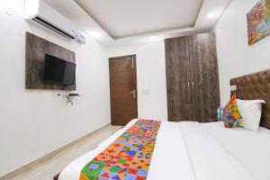 um quarto com uma cama e uma televisão na parede em FabExpress The Premium Villa em Nova Deli