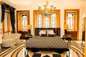 a bedroom with a bed and a couch and a chandelier at Sintra Marmoris Palace in Sintra