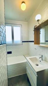 ein Bad mit einem Waschbecken, einer Badewanne und einem Fenster in der Unterkunft TI Huel in Camaret-sur-Mer