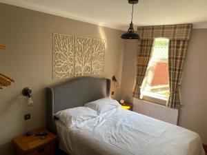 a bedroom with a bed and a window at Houghton Park Holiday Cottage in Newcastleton