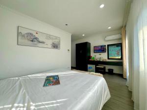 Un dormitorio con una cama blanca con una revista. en Hanoi Elpis Hotel, en Hanói