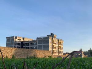 a building behind a brick wall with a grass field at Rorot 1 bedroom Kapsoya with free wifi and great views! in Eldoret