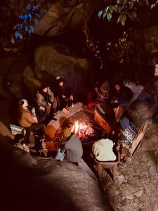 Un groupe de personnes assises autour d'un feu dans une grotte dans l'établissement Utopia Dharamkot Mcleodganj, à Dharamshala