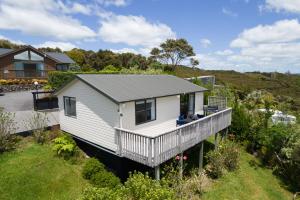 a small white house with a deck in a yard at Paihia Coastal 2 Bedroom Cottages in Haruru