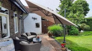 a patio with chairs and an umbrella in a yard at B&B de Maaskei in Guelle