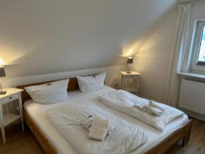een wit bed met twee handdoeken erop bij Kegelrobbe in Wyk auf Föhr