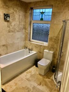 baño con bañera, aseo y ventana en Two the Manor Born 3 bedroom house en Tynemouth