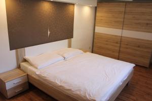 Schlafzimmer mit einem weißen Bett und Holzboden in der Unterkunft Suterénový apartmán v centre in Piešťany