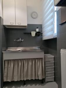 uma cozinha com um lavatório e um relógio na parede em Coccinella em Montesilvano