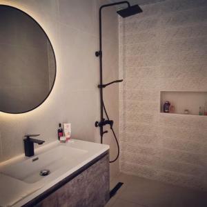 ein Bad mit einer Dusche, einem Waschbecken und einem Spiegel in der Unterkunft My Resort in Al Rahba