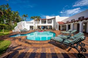 uma casa com uma piscina com cadeiras e uma casa em Lalaria Ocean Villa Suite 3 em Ballito