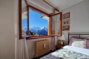 a bedroom with a window with a view of mountains at - La Casetta di Legno - i colori della natura in Foppolo
